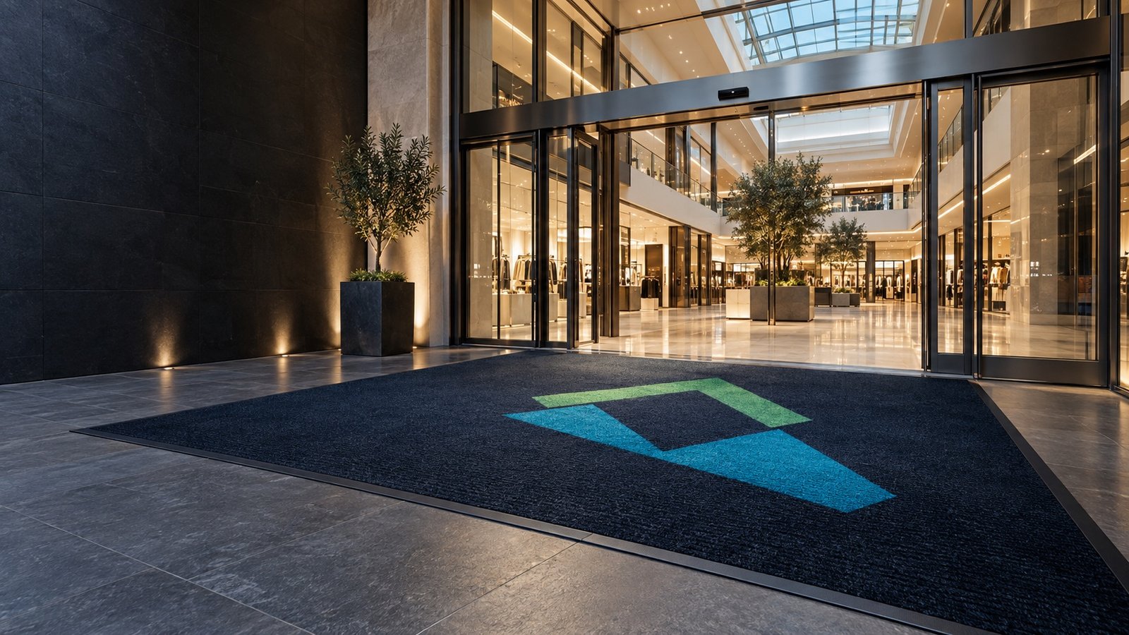 Gran entrada de centro comercial moderno con felpudo azul de gran formato y símbolo geométrico