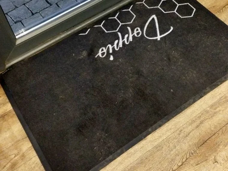 Felpudo oscuro con logotipo decorativo