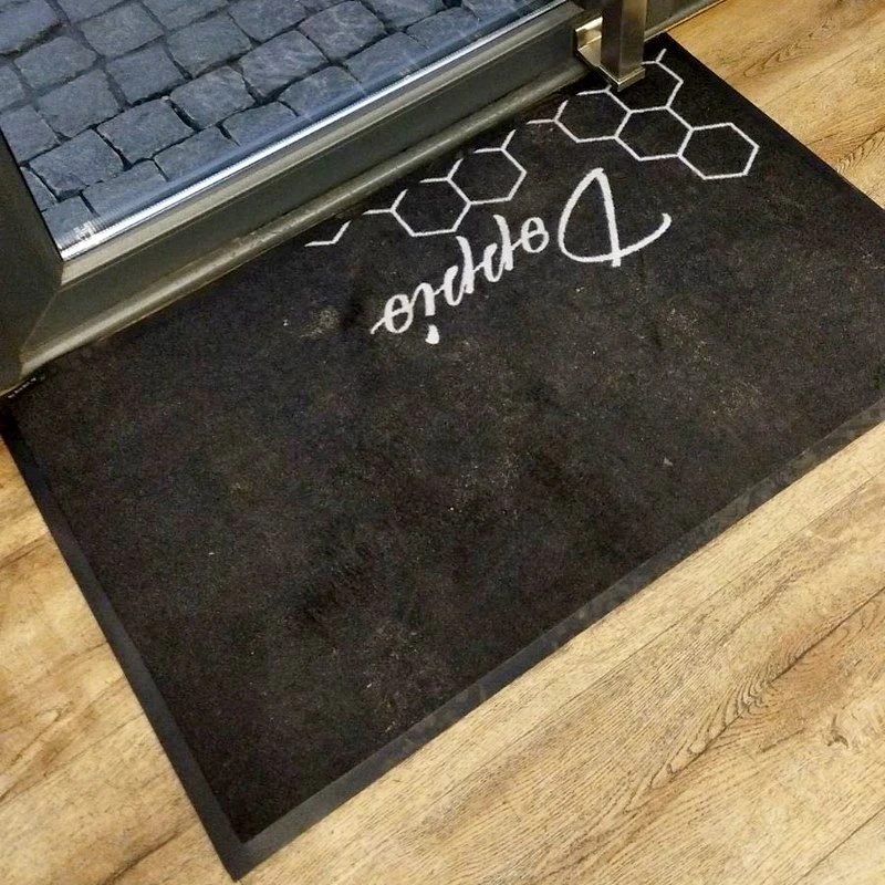 Felpudo oscuro con logotipo decorativo