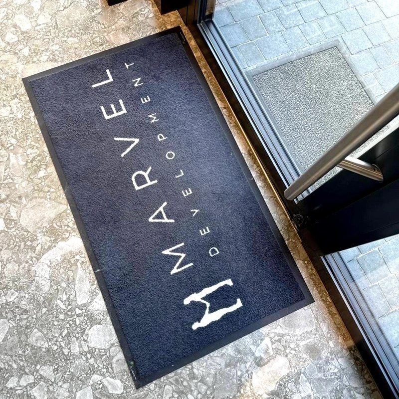 Felpudo con logotipo Marvel junto a una puerta
